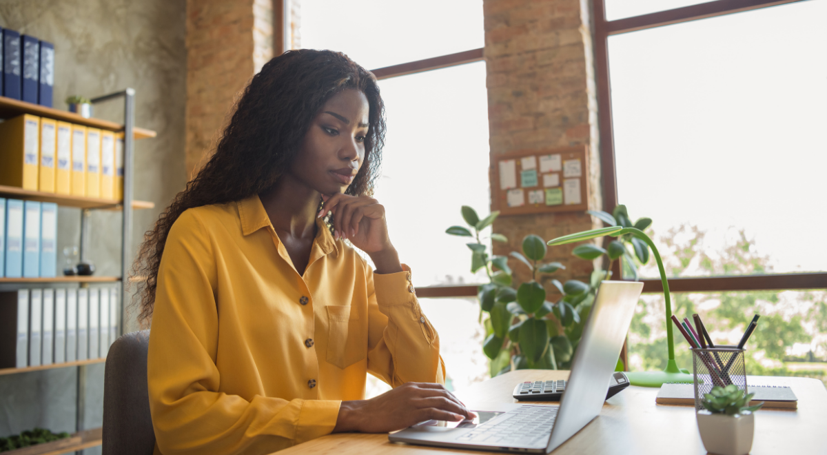 woman sitting at desk typing on laptop