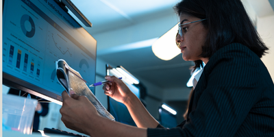 woman at computer desk reading data charts
