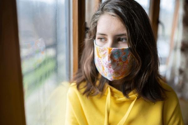 Woman sitting at window with mask on